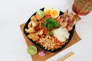 laksa, laksa curry made from vermicelli, noodles, bean sprouts, egg, tofu lime, and shrimp with a spicy soup sauce that is rich in spices. laksa served on bowl, isolated on white background. photo