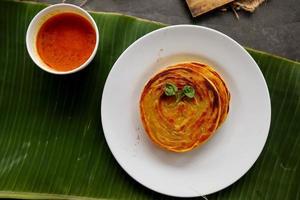 paratha bread or canai bread or roti maryam, favorite breakfast dish. served on banana leave photo