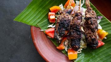 sate buntel or satay buntel is satay made from minced mutton wrapped in mutton fat and then grilled. seasoning with tomatoes, shallots, pepper, cabbage photo