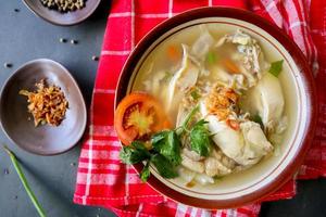Chicken soup served with vegetables, tomatoes, celery in a bowl, spoon and fork. with black background photo