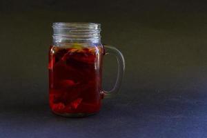 wedang uwuh is traditional herbal drink from indonesia. made from cinnamon, nutmeg and cloves leaves. Another ingredient is wood from the secang tree, ginger and lump sugar on black background photo