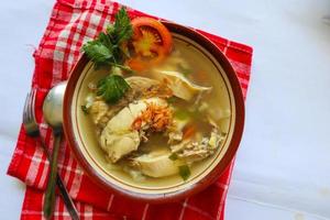 Chicken soup served with vegetables, tomatoes, celery in a bowl, spoon and fork. with black background photo