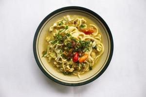 Mie godog Jawa or bakmi jawa or java noodle or Mie rebus or boiled noodles with spoon and fork. Indonesian traditional street food noodles from java, indonesia on white backgroud photo