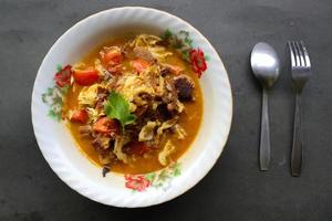 Goat Curry or gulai kambing, food from asia. Delicious goat meat curry served in a bowl.served with tomato, seasoning, celery and cabbage photo