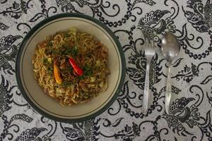 Mie Goreng Jawa or bakmi jawa or java noodle with spoon and fork. Indonesian traditional street food noodles from central java or Yogyakarta, indonesia on white background photo