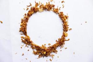 bawang goreng or Pile of fried Indonesian Deep Onion fries or shallots with circle shape isolated on white background. photo