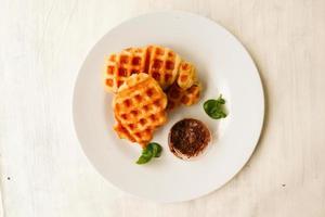 gofre croissant o croffle con salsa de chocolate servido en caja y fondo blanco foto