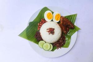 nasi lemak, es un malayo tradicional hecho con huevos cocidos, frijoles, anchoas, salsa de chile, pepino. aislado sobre fondo blanco foto