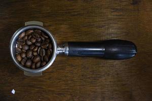 porta filter with ground coffee and coffee bean on table photo