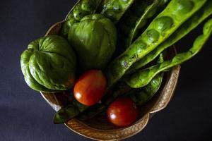 tropical tomatoes with jipang or labu siam or chayote and onion are served in a basket isolated on black background photo