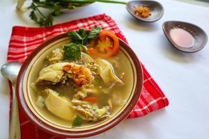 Chicken soup served with vegetables, tomatoes, celery in a bowl, spoon and fork. with black background photo