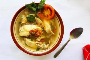 Chicken soup served with vegetables, tomatoes, celery in a bowl, spoon and fork. with black background photo