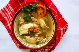 Chicken soup served with vegetables, tomatoes, celery in a bowl, spoon and fork. with black background photo