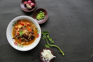 Goat Curry or gulai kambing, food from asia. Delicious goat meat curry served in a bowl.served with tomato, seasoning, celery and cabbage photo