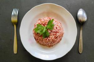 arroz rojo al vapor o nasi merah servido en un plato aislado de fondo negro foto