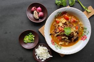 Goat Curry or gulai kambing, food from asia. Delicious goat meat curry served in a bowl.served with tomato, seasoning, celery and cabbage photo