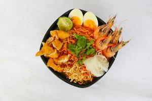 laksa, laksa curry made from vermicelli, noodles, bean sprouts, egg, tofu lime, and shrimp with a spicy soup sauce that is rich in spices. laksa served on bowl, isolated on white background. photo