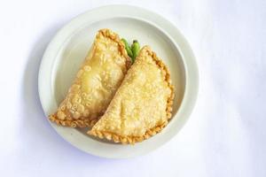 pastie cake or pastry cake or kue pastel served with green chili in little plate on wood background. indonesian pastel cake photo