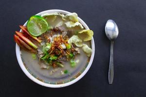 sop kaki kambing una comida tradicional de betawi, yakarta indonesia, hecha de cordero o cordero, despojos, especias. aislado sobre fondo negro. Esta comida es como estofado de cordero sobre fondo negro foto