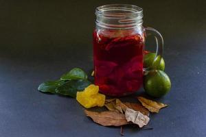 wedang uwuh is traditional herbal drink from indonesia. made from cinnamon, nutmeg and cloves leaves. Another ingredient is wood from the secang tree, ginger and lump sugar on black background photo