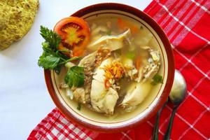 Chicken soup served with vegetables, tomatoes, celery in a bowl, spoon and fork. with black background photo