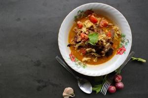 Goat Curry or gulai kambing, food from asia. Delicious goat meat curry served in a bowl.served with tomato, seasoning, celery and cabbage photo