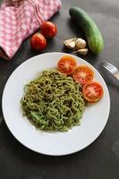 green noodles, or Spinach pasta , Zucchini raw vegan pasta dip, and tomatoes on plate. photo