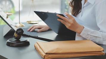 Business and lawyers discussing contract papers with brass scale on desk in office. Law, legal services, advice, justice and law concept picture with film grain effect video