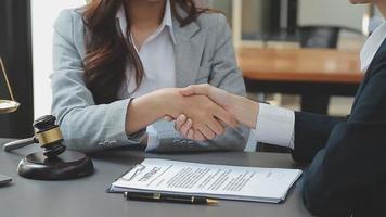 Business and lawyers discussing contract papers with brass scale on desk in office. Law, legal services, advice, justice and law concept picture with film grain effect video