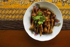 Spicy chicken feet with celery, chili, onion, garlic served with a white plate isolated from a black background. photo