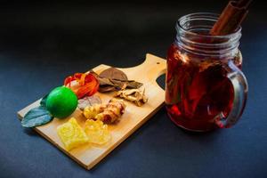 wedang uwuh is traditional herbal drink from indonesia. made from cinnamon, nutmeg and cloves leaves. Another ingredient is wood from the secang tree, ginger and lump sugar on black background photo