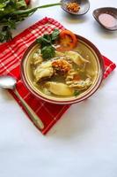 Chicken soup served with vegetables, tomatoes, celery in a bowl, spoon and fork. with black background photo