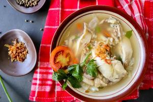 Chicken soup served with vegetables, tomatoes, celery in a bowl, spoon and fork. with black background photo