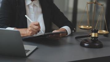 Business and lawyers discussing contract papers with brass scale on desk in office. Law, legal services, advice, justice and law concept picture with film grain effect video