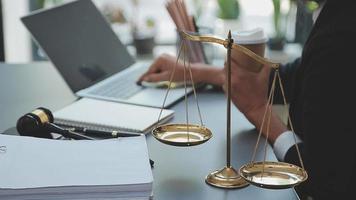 Business and lawyers discussing contract papers with brass scale on desk in office. Law, legal services, advice, justice and law concept picture with film grain effect video