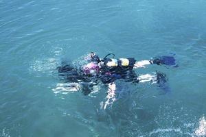 vista superior del buzo nadando bajo el agua y examina el lecho marino. burbujas de buzo que vienen de abajo hacia la superficie. foto