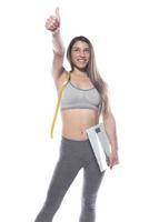 Female model holding scale and measuring tape over white background photo