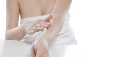 Beautiful skinned woman applying body lotion on white background photo