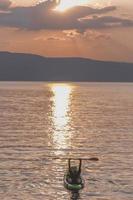 Handsome sporty man is kayaking on sunset photo