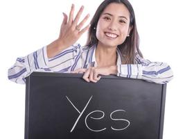 Beautiful Asian female model pointing on wedding ring on her hand and holding blackboard with YES sign on it. photo