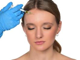 young woman gets injection of botox in her face. Woman in beauty salon. plastic surgery clinic. photo