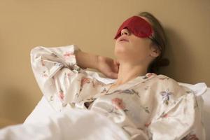 Tired woman sleeping in bed wearing blindfold sleep mask photo