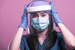 primer plano de una doctora asiática con protector facial y traje de ppe para el brote de coronavirus foto