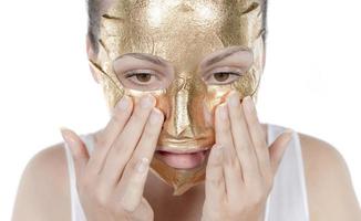 procedimiento cosmético, la cara de la mujer con máscara de oro sobre fondo blanco