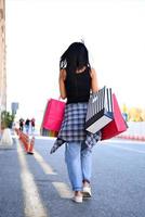 Beautiful woman walking on the street with shopping bags. Trendy female model in the city holdingshopping bags. photo