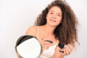 beautiful young smiling woman apply makeup with brush. isolated photo