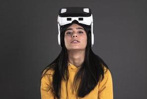 Pretty cute excited female in VR headset looking up and trying to touch objects in virtual reality photo