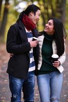 Mixed couple In park enjoying each other and drinking coffee photo