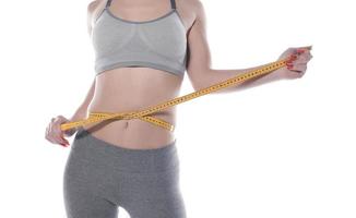 Young woman measure her waist with measure tape photo