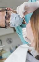 dentist curing patient's teeth filling cavity. Dentist working with professional equipment in clinic. photo